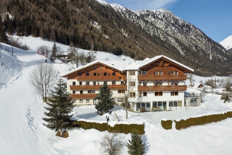 Hotel im Schnee vor den Bergen von Vals in Südtirol